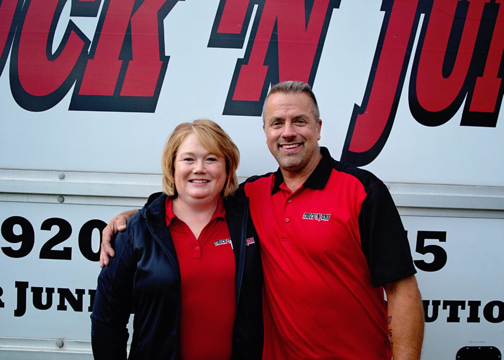 The Truck 'N Junk Owners pose in front of a junk removal truck Eviction Cleanout Services